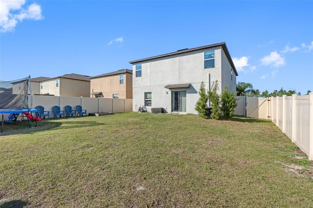 rear view of house with a yard and a trampoline