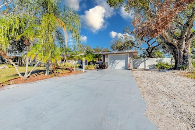 view of front of home with driveway, an attached garage, and fence