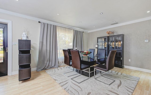 dining area with wood finished floors, visible vents, and crown molding