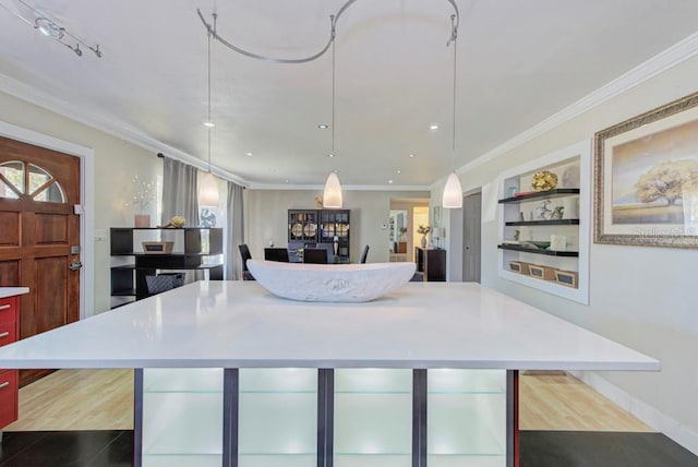 kitchen featuring a kitchen island, light countertops, crown molding, and hanging light fixtures