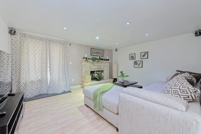 bedroom featuring light wood-type flooring, a stone fireplace, and recessed lighting