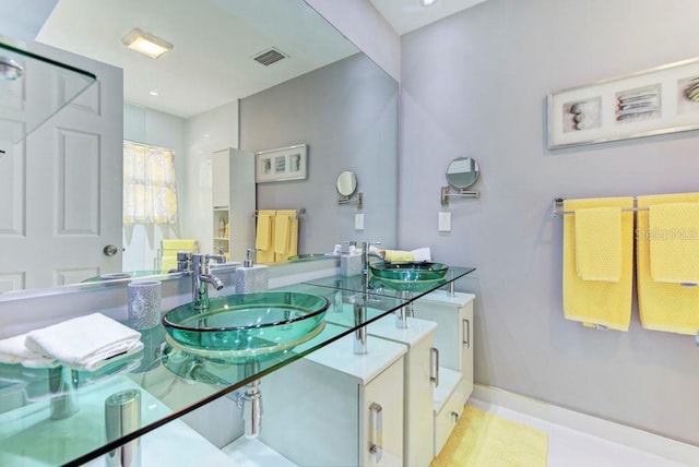 bathroom featuring double vanity, a sink, visible vents, and baseboards