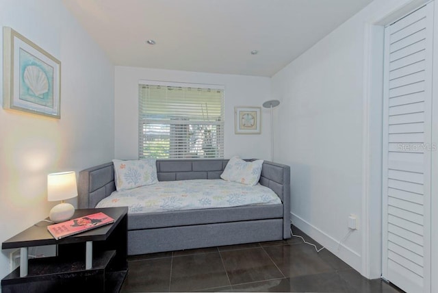 bedroom with baseboards and dark tile patterned flooring