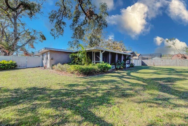 back of house with a lawn, a fenced backyard, and a sunroom