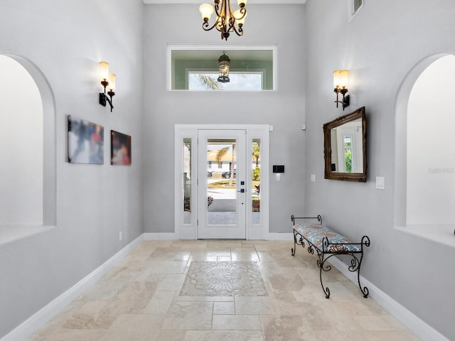 foyer entrance featuring a towering ceiling and a chandelier