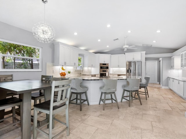 kitchen with sink, kitchen peninsula, stainless steel appliances, decorative backsplash, and white cabinets
