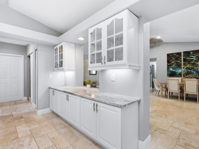 kitchen featuring white cabinetry, lofted ceiling, and light stone counters