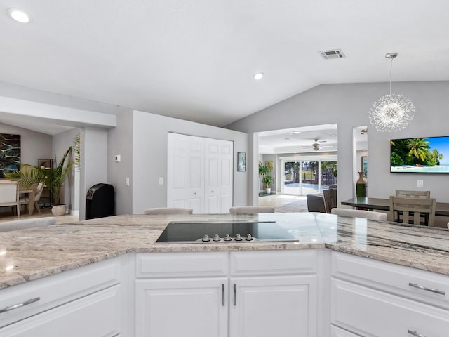 kitchen with pendant lighting, white cabinetry, lofted ceiling, black electric stovetop, and light stone counters