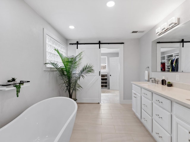 bathroom with a washtub, vanity, and tile patterned flooring