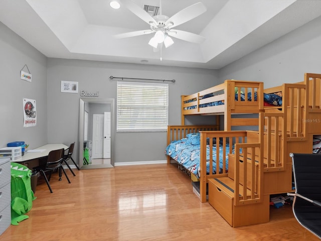bedroom featuring a tray ceiling and light hardwood / wood-style flooring