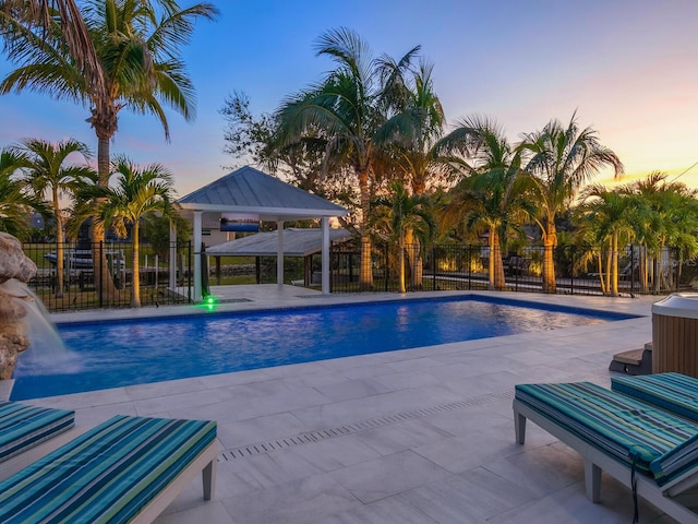pool at dusk featuring a gazebo, pool water feature, and a patio area
