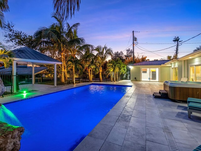pool at dusk featuring an outbuilding, a patio, a hot tub, and a gazebo