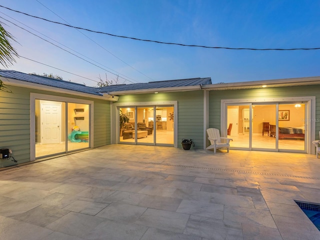 back house at dusk featuring a patio
