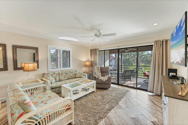 living room with ornamental molding, light hardwood / wood-style floors, and ceiling fan