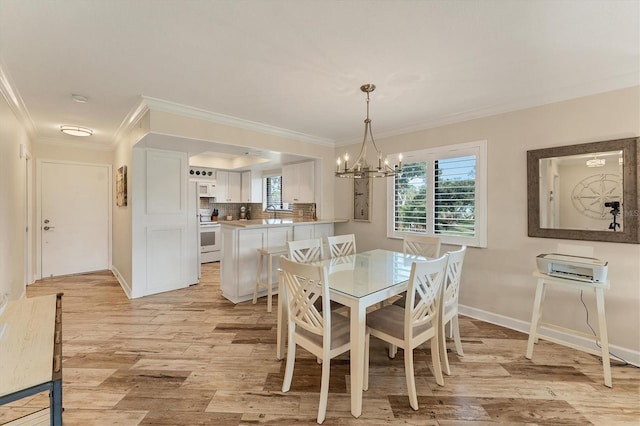 dining room featuring a notable chandelier, light hardwood / wood-style flooring, ornamental molding, and sink