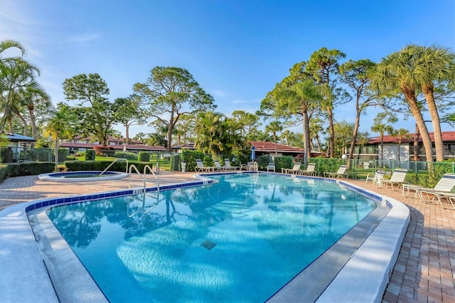 view of swimming pool featuring a hot tub and a patio