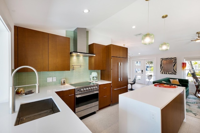 kitchen featuring electric stove, sink, pendant lighting, paneled built in fridge, and wall chimney exhaust hood