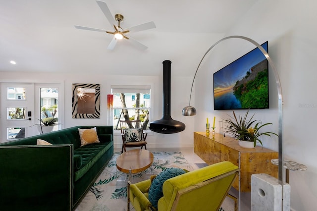 living room featuring a wood stove and ceiling fan