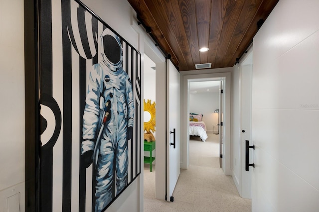 corridor featuring wooden ceiling and a barn door