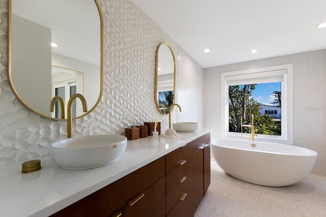 bathroom with vanity, a washtub, and tile walls