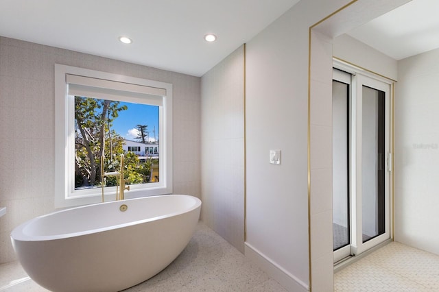 bathroom with tile walls and a tub to relax in