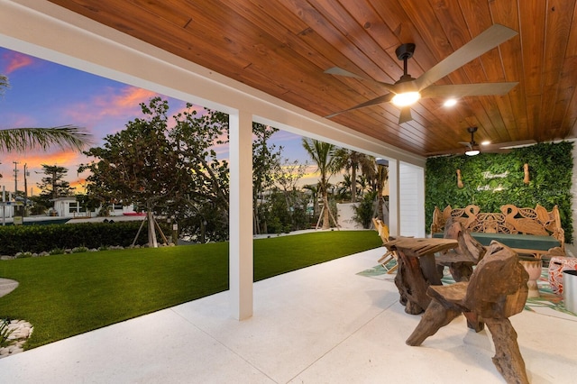 patio terrace at dusk with ceiling fan and a lawn