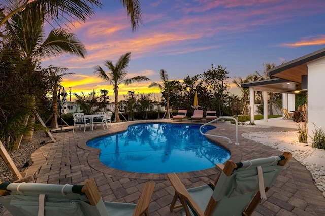 pool at dusk with a patio area