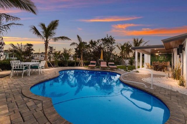 pool at dusk featuring a patio area