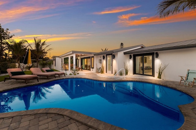 pool at dusk with a patio area