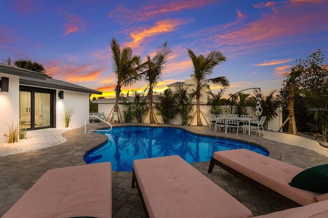 pool at dusk featuring a patio