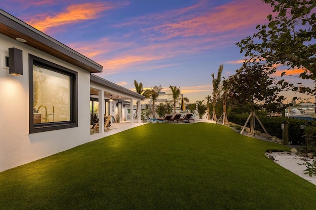 yard at dusk featuring a patio area