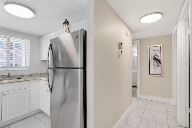 2211 Sunset Dr Unit E3, Bradenton, FL 34207 - kitchen with light tile patterned flooring, sink, white cabinets, and stainless steel refrigerator
