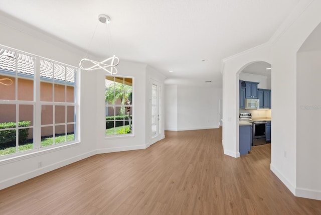 unfurnished dining area featuring an inviting chandelier, ornamental molding, and light hardwood / wood-style flooring