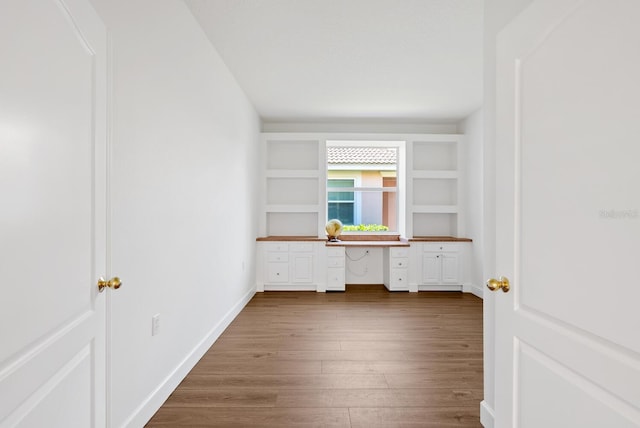 interior space featuring hardwood / wood-style flooring, built in desk, and built in shelves