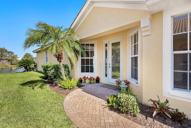 entrance to property with a lawn and stucco siding