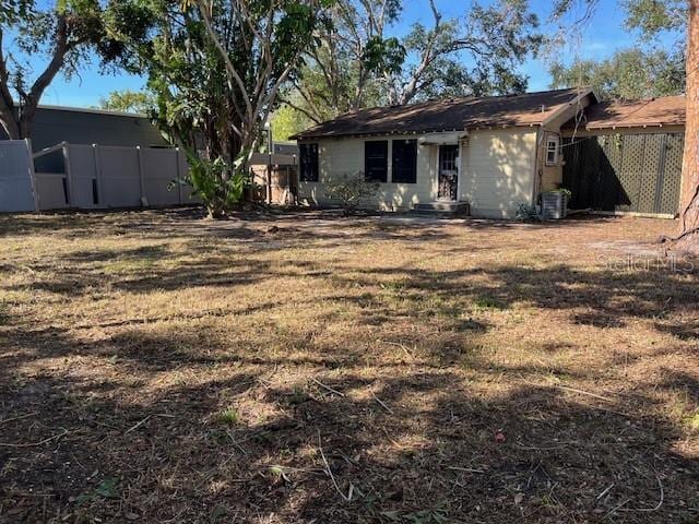 rear view of house with a yard and central AC