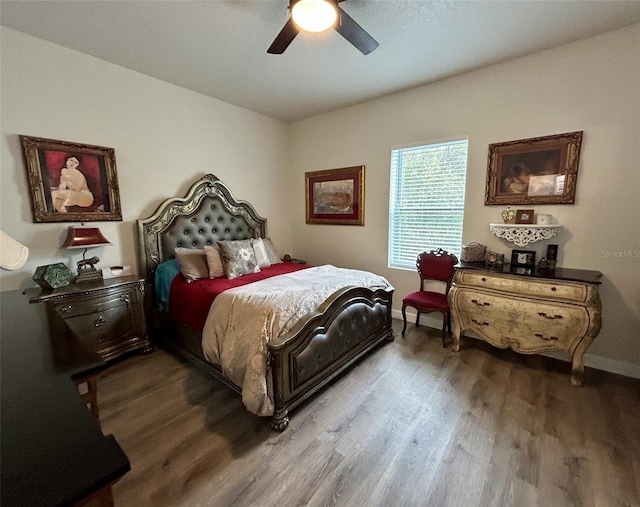 bedroom with ceiling fan, wood finished floors, and baseboards