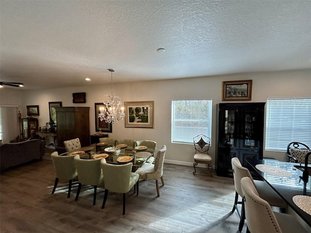 dining space with wood-type flooring, a chandelier, and a textured ceiling