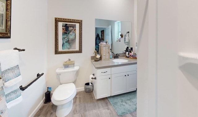 bathroom featuring toilet, wood finished floors, vanity, and baseboards