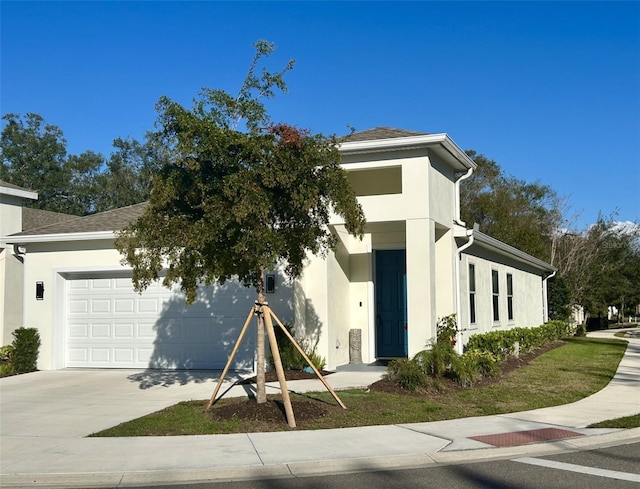 view of front facade with driveway, roof with shingles, a garage, and stucco siding