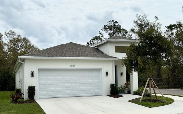 ranch-style home featuring an attached garage, fence, driveway, roof with shingles, and stucco siding