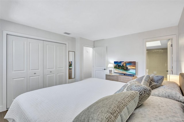 bedroom with connected bathroom, hardwood / wood-style floors, and a closet