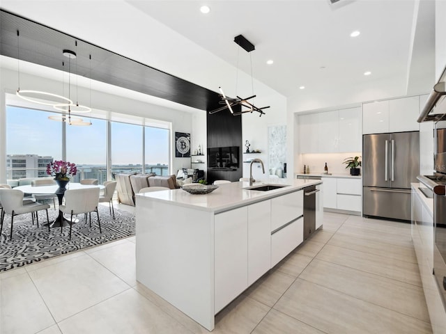 kitchen with hanging light fixtures, white cabinetry, appliances with stainless steel finishes, and an island with sink