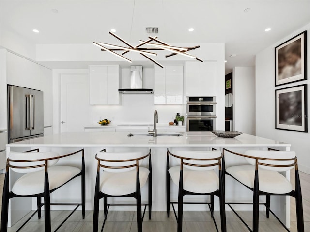 kitchen featuring stainless steel appliances, sink, white cabinets, and wall chimney exhaust hood