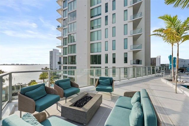 view of patio / terrace with a water view, a balcony, and an outdoor fire pit