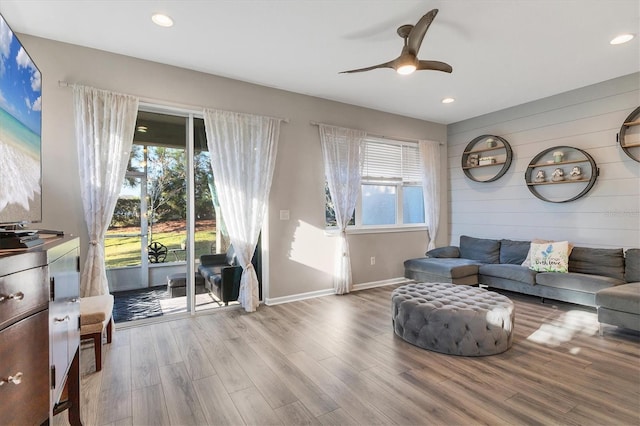 living room featuring hardwood / wood-style floors, ceiling fan, and wood walls