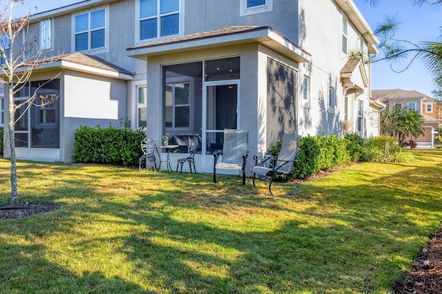 rear view of property with a sunroom and a lawn