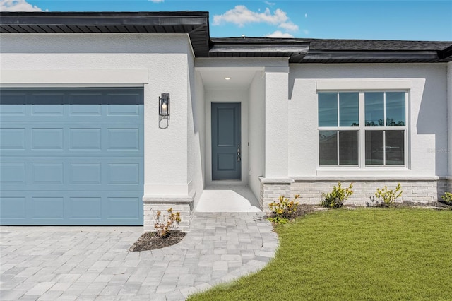 view of exterior entry with a garage and a lawn