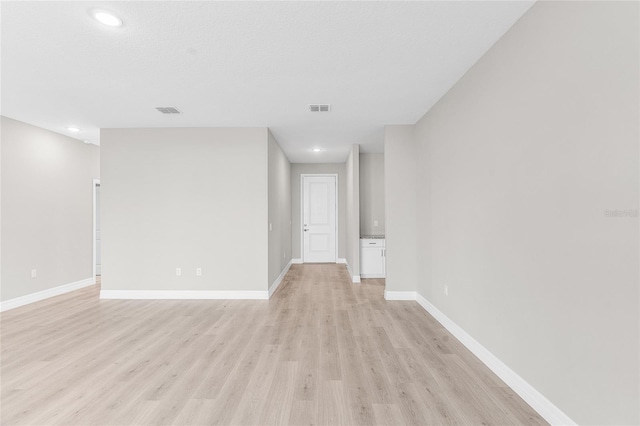 spare room with a textured ceiling and light wood-type flooring