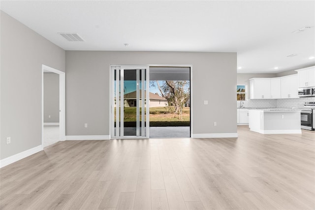 unfurnished living room featuring sink and light hardwood / wood-style floors